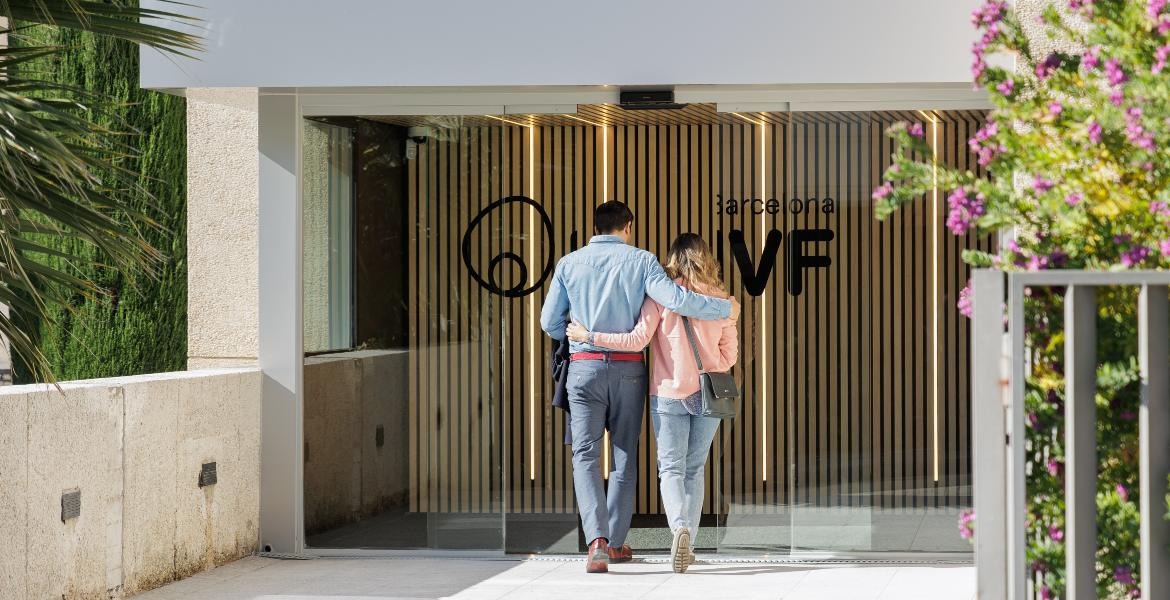 Couple entrant ensemble dans l’entrée de la clinique Barcelona IVF, centre moderne de traitements de fertilité en Espagne.