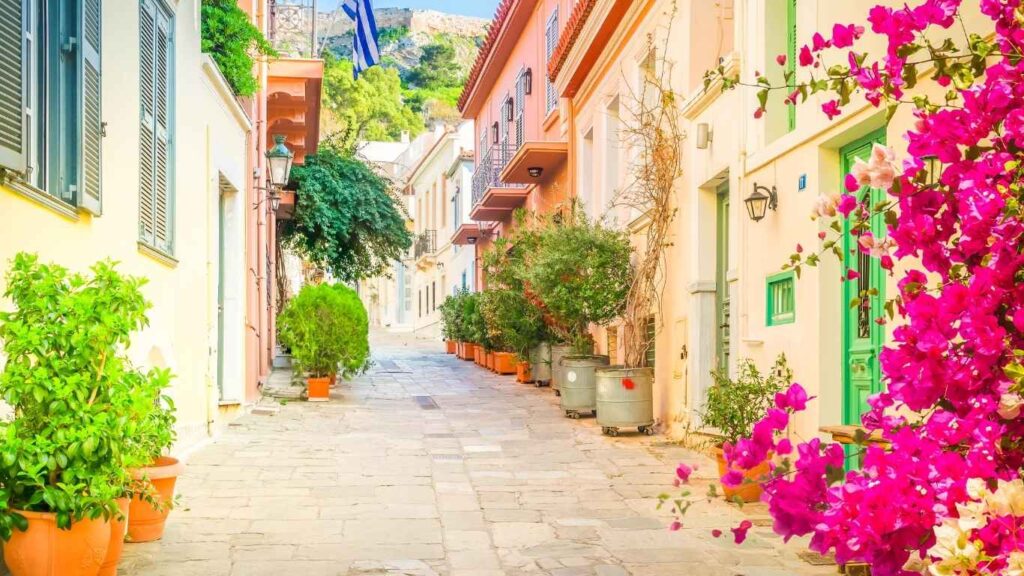 Ruelle pittoresque aux maisons colorées et fleurs roses en Grèce, symbole d’un environnement accueillant pour le don d’ovocytes et la FIV